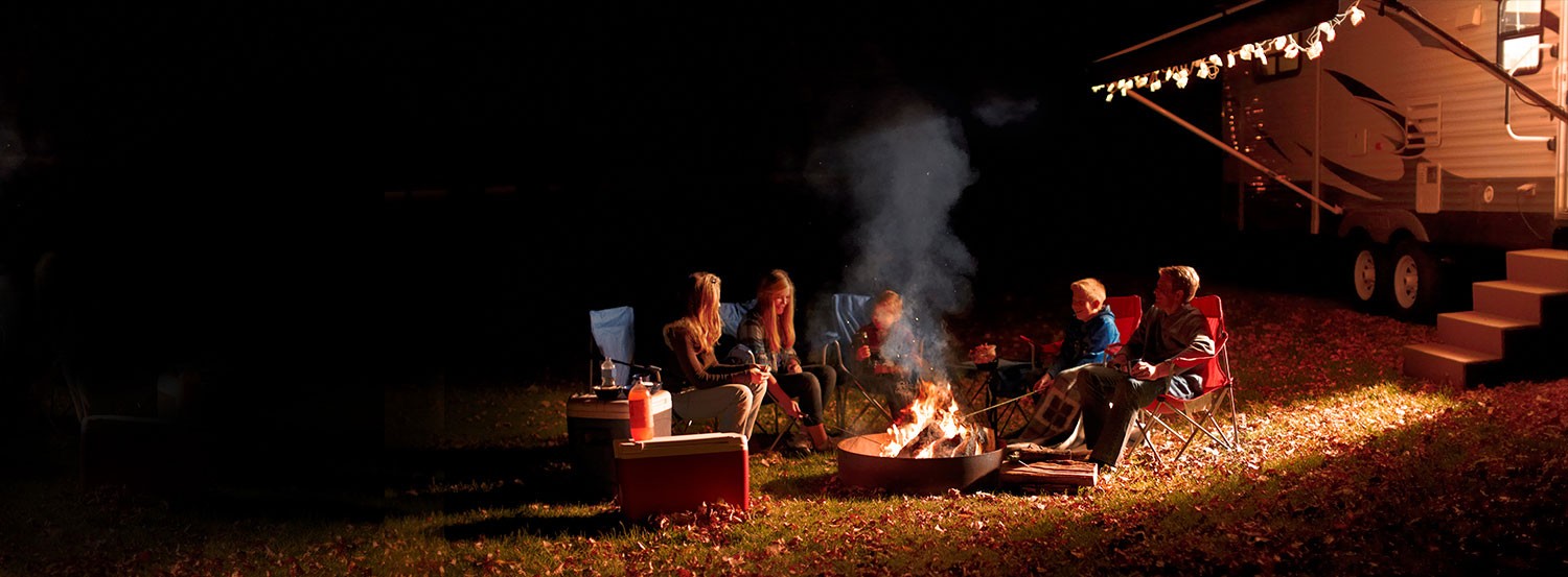 Family around campfire, RV with lights