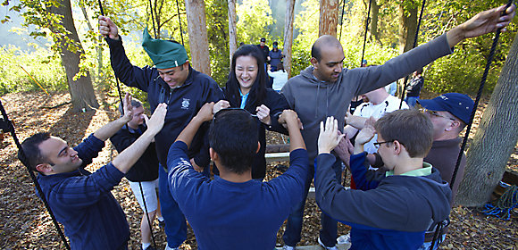 A group of Kohler Co. employees stands in a circle in the woods as part of a team-building exercise