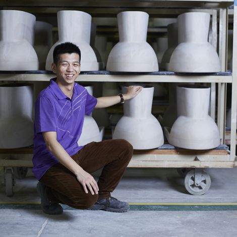 A Kohler Co. employee wearing a purple shirt kneels down to inspect racks of KOHLER toilets