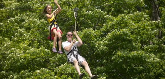 A man and a girl zipline during Kohler Co. family fun day