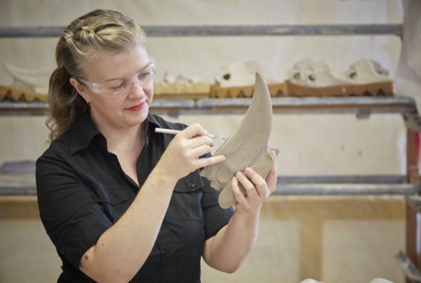 An artist in Kohler Co.'s Arts/Industry program uses a small tool to shape a clay sculpture