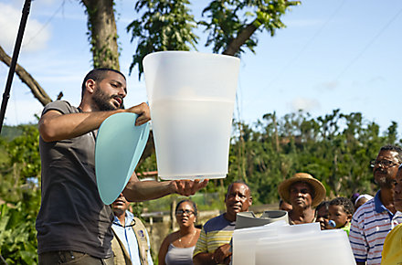 A man demonstrates how to use KOHLER® Clarity™ water filters to a group of people in Puerto Rico after the island was devastated by Hurricane Maria