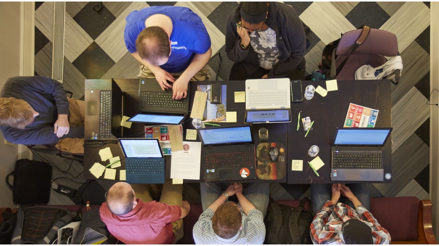 A top-down view of six participants in Kohler Co.'s Rotational Program. Each is looking at their own laptop as they sit around a table together.