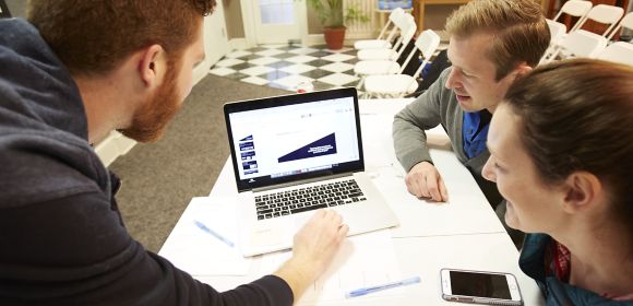 Ryan Kalcich, IT Systems project manager at Kohler Co., looks at a laptop with two other employees