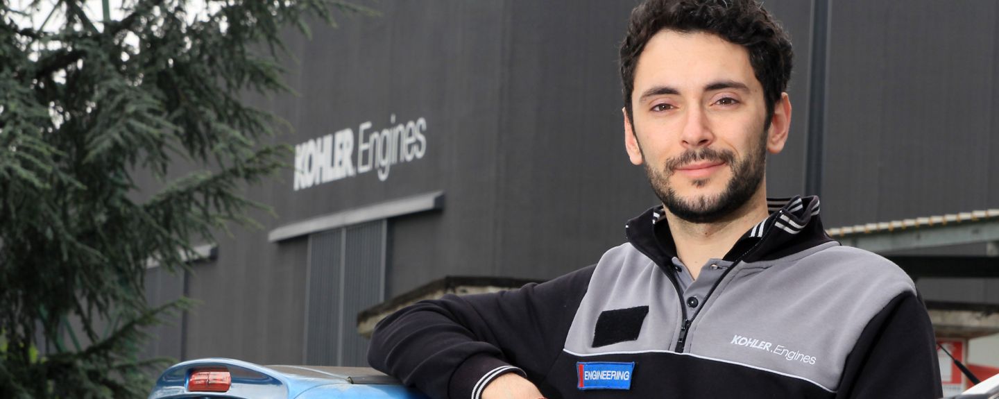 Engineer Federico Baldisserr of Kohler Engines in Reggio Emilia, Italy, poses with his arm on a car in front of a Kohler Engines facility.