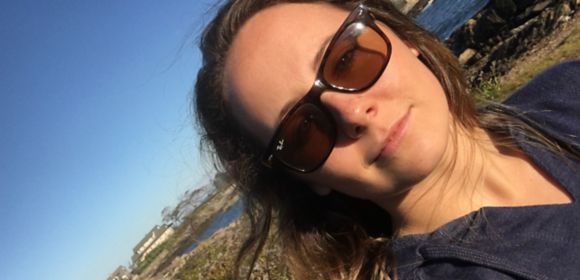 Megan Kolb, an area associate on Kohler Co.'s Retail Faucets marketing team, stands in the sun in front of the shoreline.
