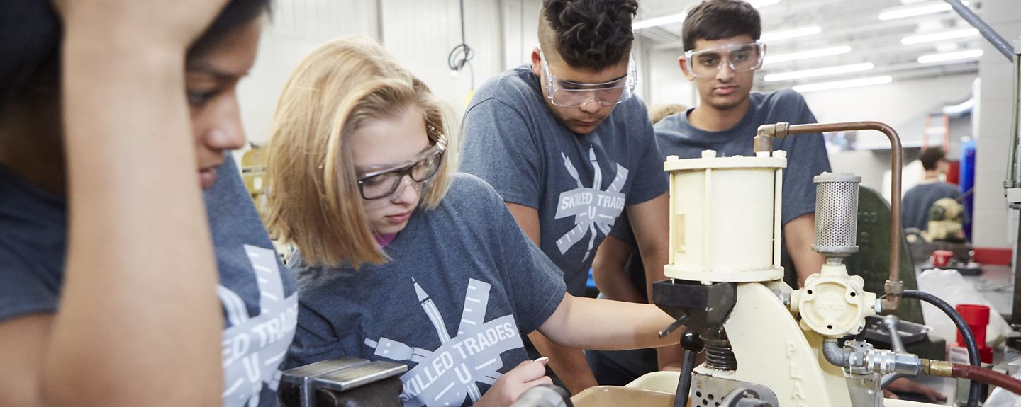 Four teenagers with t-shirts that say Skilled Trades U work on a project at Kohler