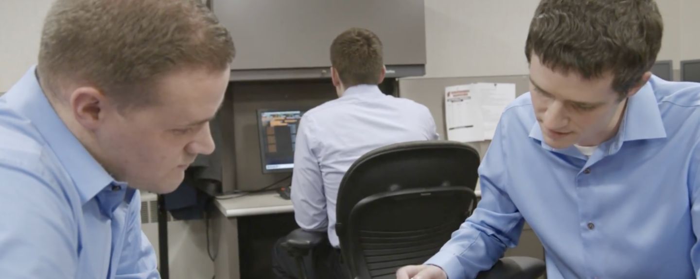 Two employees who work in finance and accounting at Kohler Co. sit together looking at a printed spreadsheet.
