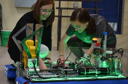 Engineer Megan Kennedy-Pierce and another Kohler Co. employee kneel on the floor by a robot they're helping build as volunteers of a Sheboygan-area robotics club