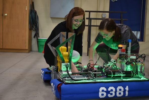 Engineer Megan Kennedy-Pierce and another Kohler Co. employee kneel on the floor by a robot they're helping build as volunteers of a Sheboygan-area robotics club