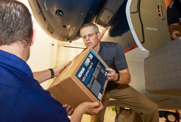 One man hands a box of KOHLER engine oil to another in Puerto Rico after a hurricane