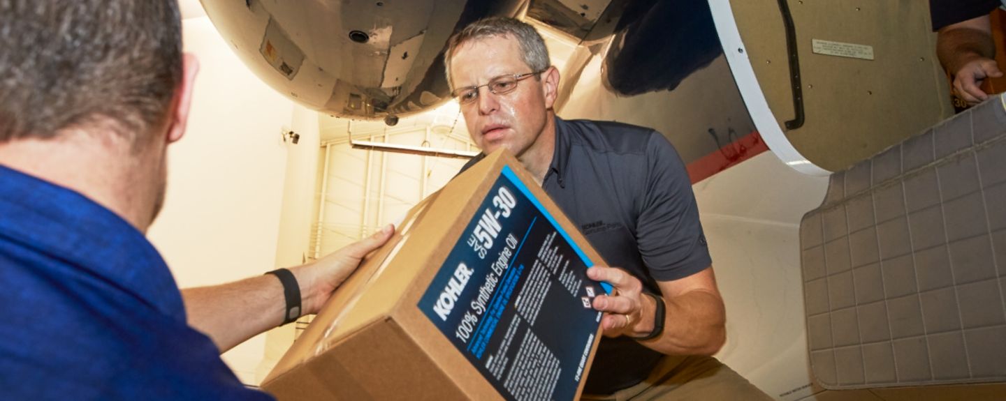 One man hands a box of KOHLER engine oil to another in Puerto Rico after a hurricane