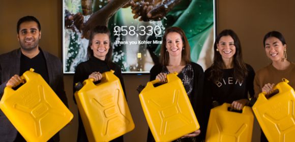 Five Kohler Mira employees stand side by side holding yellow water containers