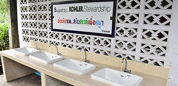 A row of four sinks in front of a sign that says Support by Kohler Stewardship