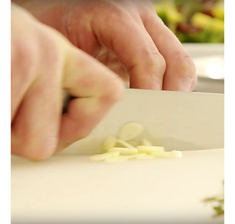 A close-up shot of someone chopping garlic with a knife
