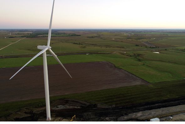 An aerial shot of a windmill in the midst of expansive farming land