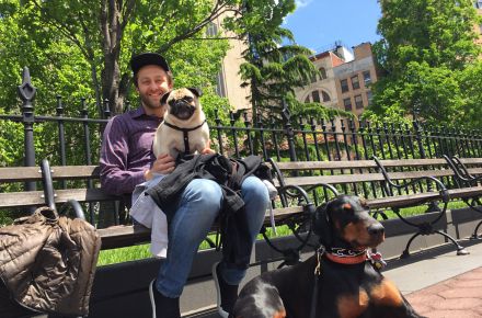 Seth Stevens, Chief Designer, Decorative Products, for Kohler Co. in Kohler, Wisconsin, sits on a park bench with one dog on his lap and another in front of him