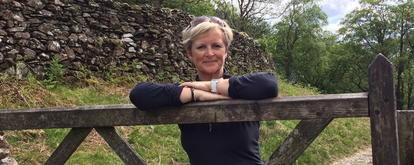 Linda Waite, stands behind a fence with her arms crossed.