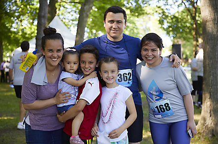 A family gathers with their arms around each other as the father, a Kohler Co. employee, and one child have just finished a fundraising run or walk together