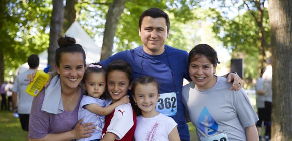 A family gathers with their arms around each other as the father, a Kohler Co. employee, and one child have just finished a fundraising run or walk together