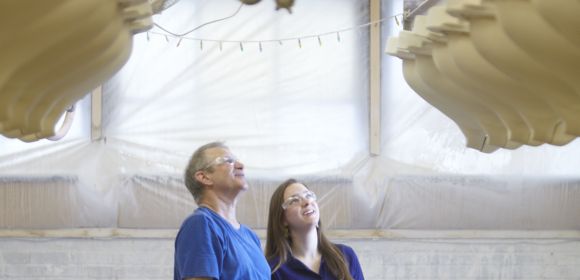 Two KOHLER employees with safety glasses look up at a system designed to capture manufacturing waste