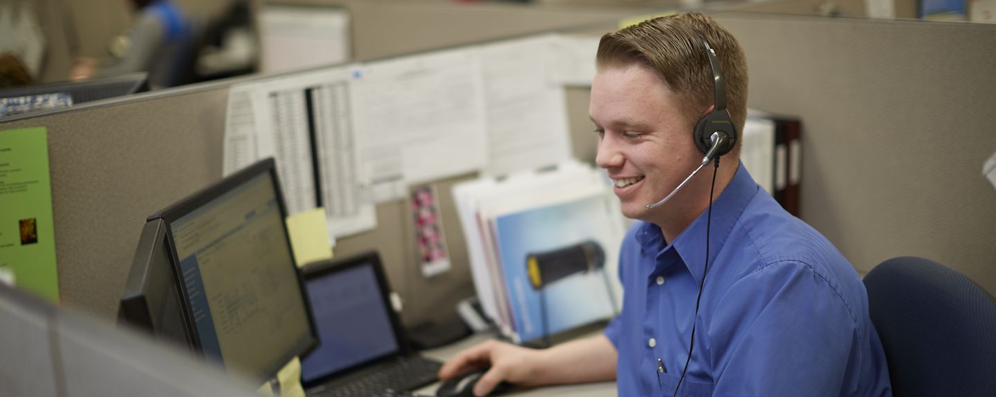 Adam Braunel, Customer Service – Supervisor Customer Care, at Kohler Co. works at a cubicle talking to a customer via his headset