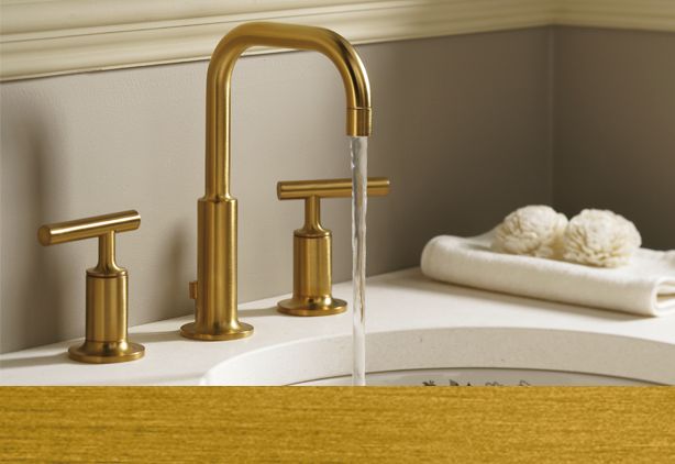 Bathroom faucet in brushed gold with dual handles on toilet countertop