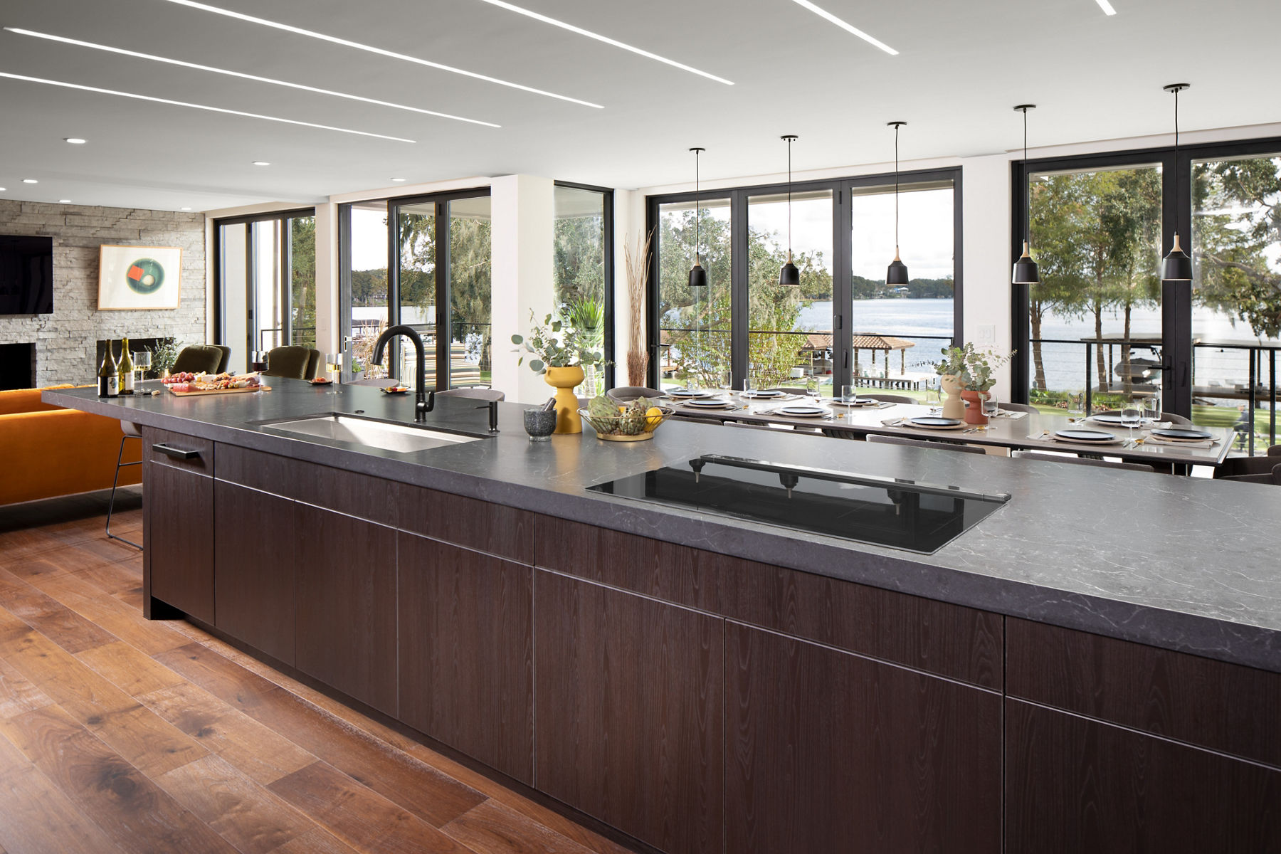Daylight in large open kitchen in view of living space with floor to ceiling windows.