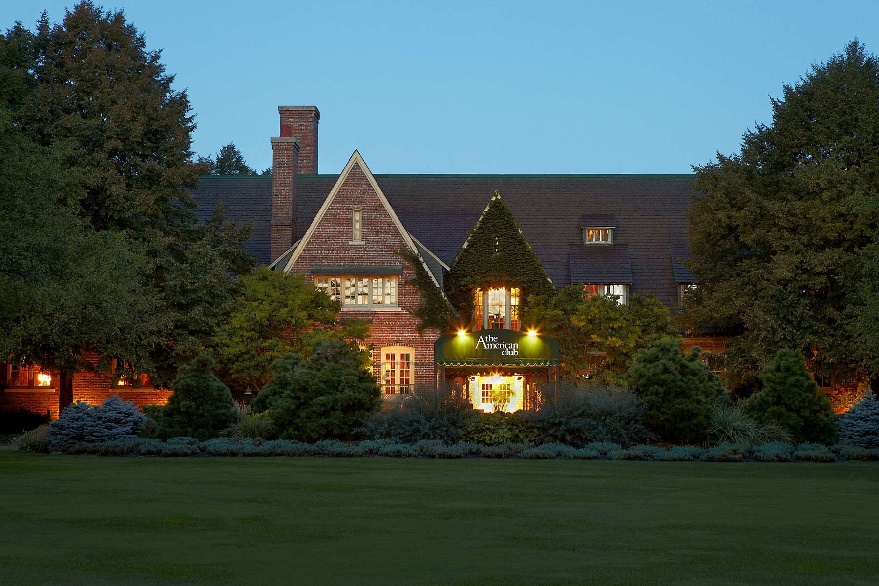 External view of the American Club at dusk with luminated exterior lighting.