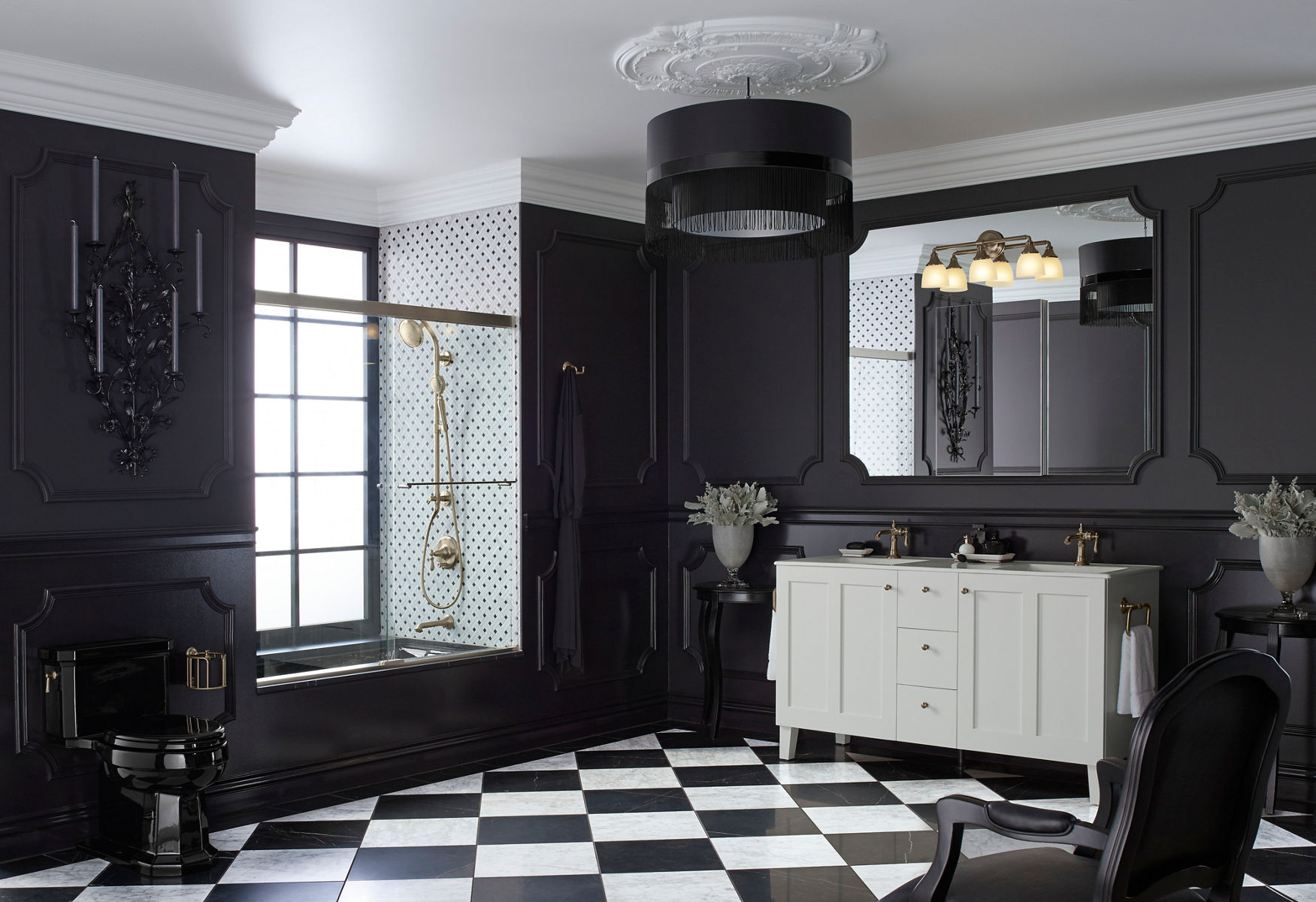 A traditional black bathroom with black KOHLER toilet, white vanity, black and white diamond pattern floor, black tub with black and white tiled shower,  and black paneled walls