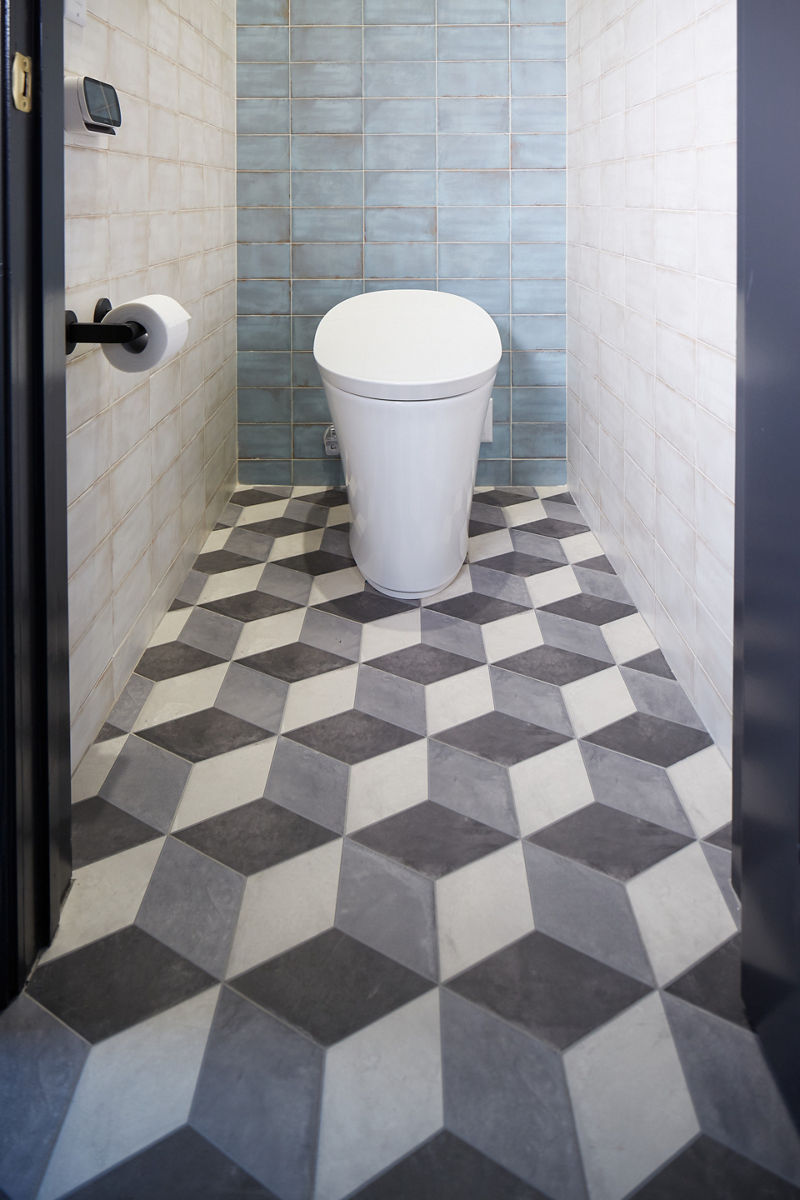 View of a bathroom with graphic patterned floor tile, light tiled walls, and a KOHLER Veil Intelligent toilet.