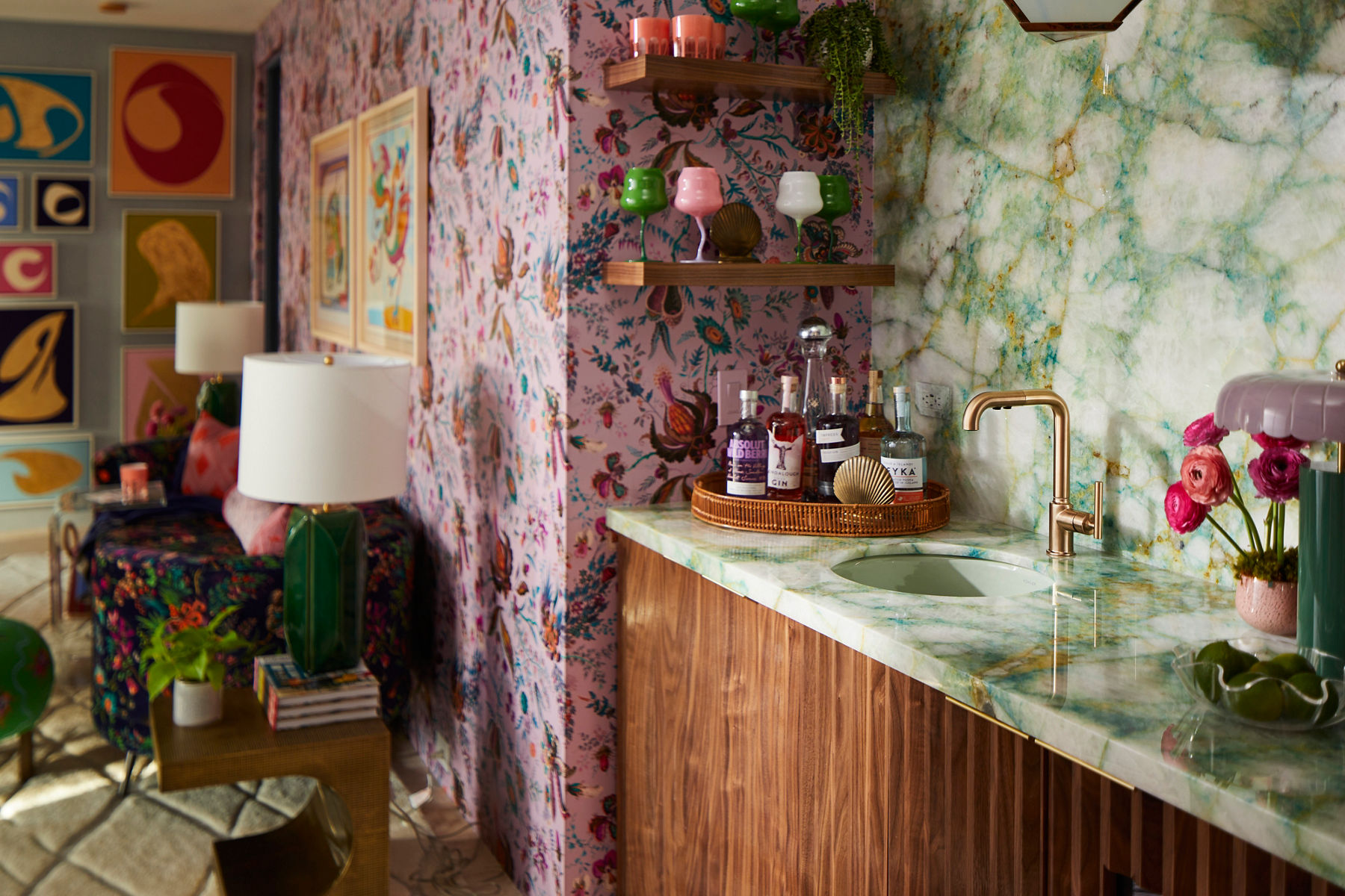 A design by Betsy Wentz with a wet bar in green and white stone and fuscia floral pring wallpaper.