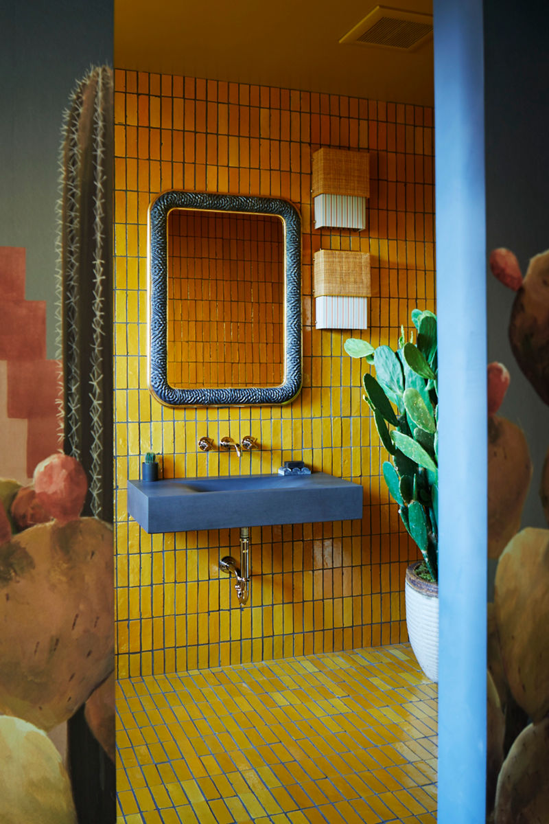A bathroom styling space with yellow wall tile and a blue stone sink and wall-mount faucet.