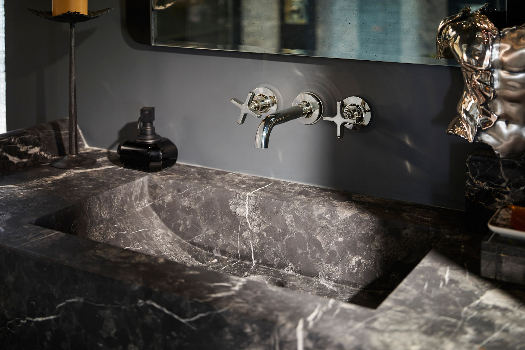 A black toilet with illuminated rear and bottom panels in a bathroom with striped stone.