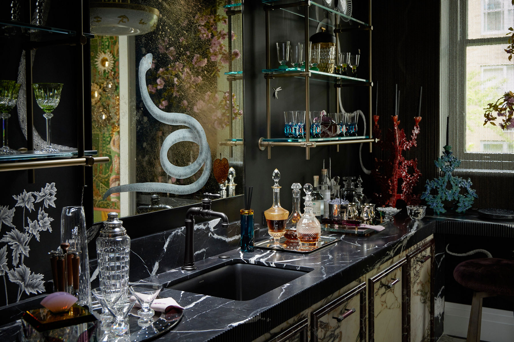 A dramatic bar space designed with black marble, giant mirrors, and decadent decor.