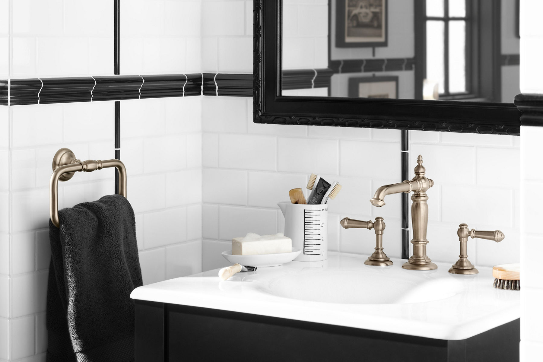 Salle de bain noire et blanche avec carreaux de métro blancs et accents noirs avec meuble-lavabo noir avec lavabo blanc et robinet de salle de bain et accessoires Artifacts en bronze brossé Vibrant.