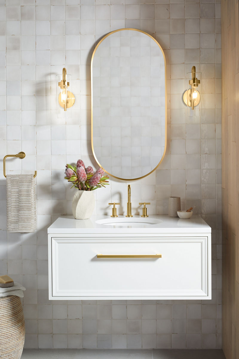An oval mirror with brushed moderne brass frame and sconce lights.