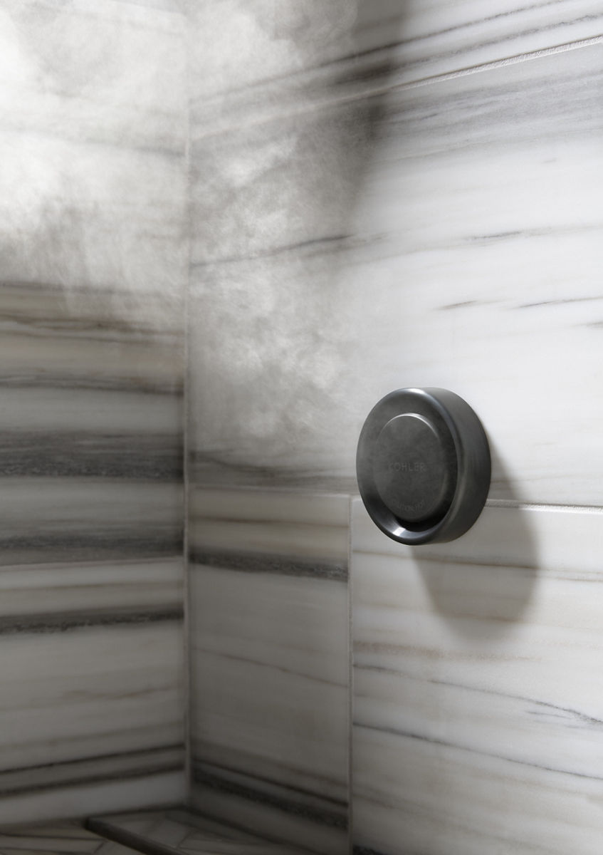 Steam emitting from a steam system attached to a white tile wall gray horizontal lines.