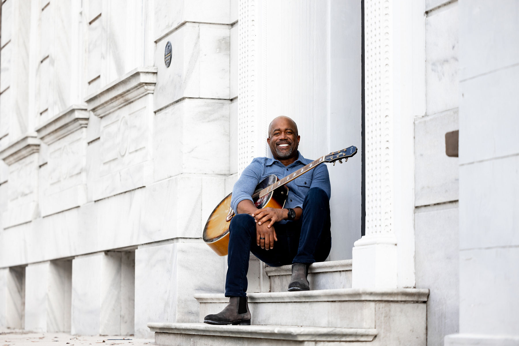 Darious Rucker, avec une guitare, est assis sur les marches à l’extérieur de la porte d’entrée de sa maison à Charleston, Caroline du Sud.