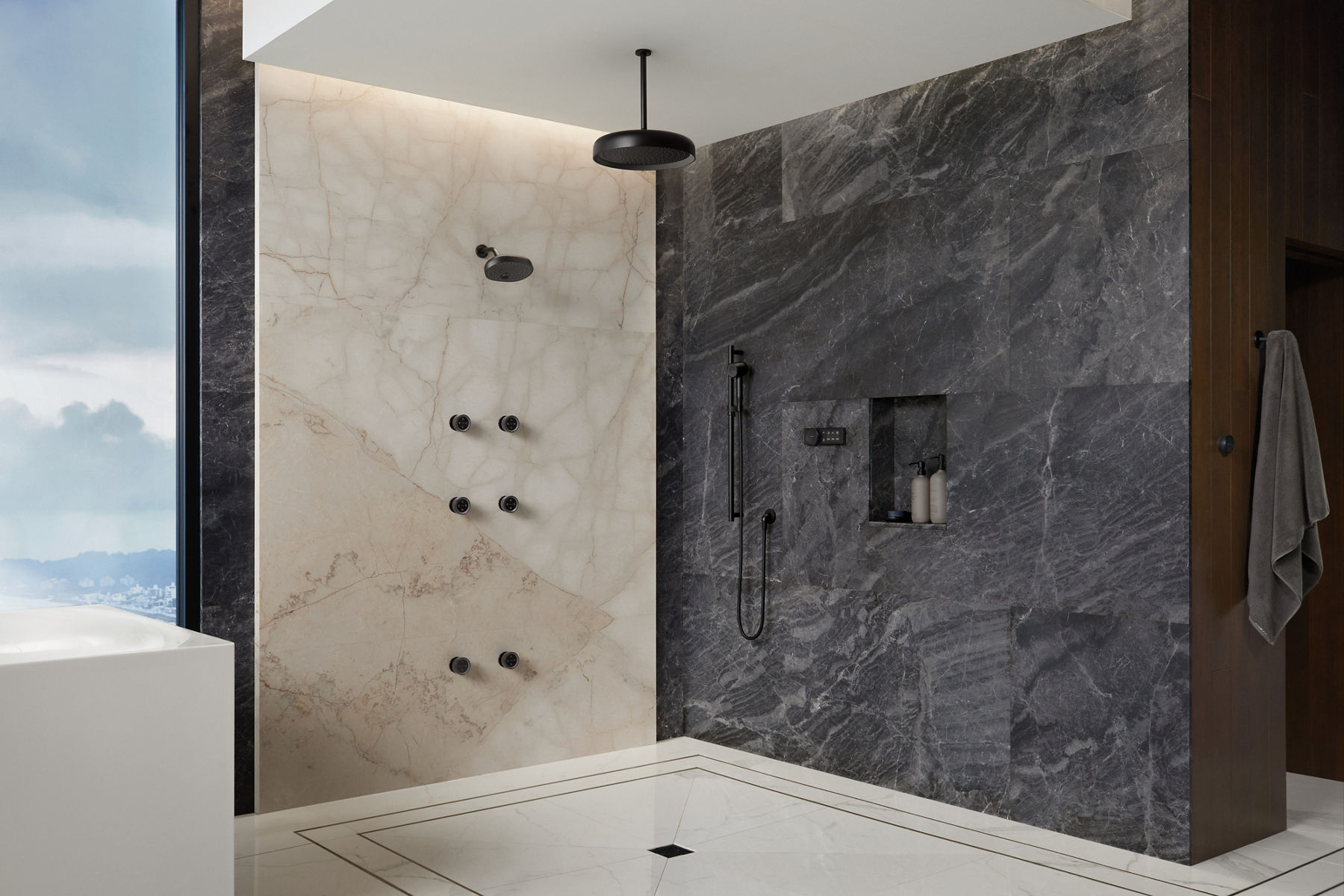 Douche complète en pierre grise et blanche, sans portes ni rideaux, avec pomme de douche à effet de pluie KOHLER noir et plusieurs pommes de douche.