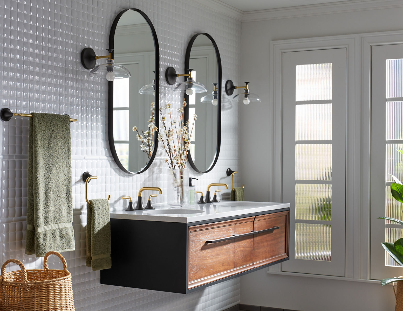Les accessoires de salle de bain KOHLER comme les contenants de savon et les bougies sont disposés sur une table en bois avec des rubans, qui semblent être enveloppés comme un panier-cadeau.