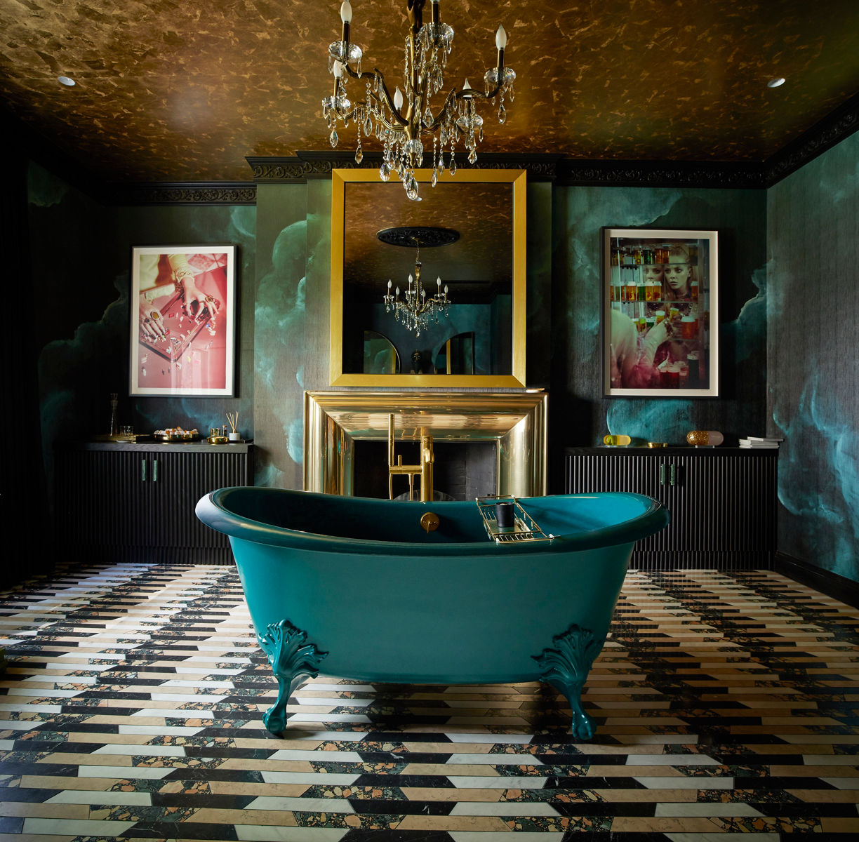 A cropped wide shot image of a beautifully eccentric bathroom designed with black and teal wallpaper, black, beige, and white marble floor tiling, and black panel cabinets on each side of a fireplace mantle. There's a teal tub at the center front of the image.