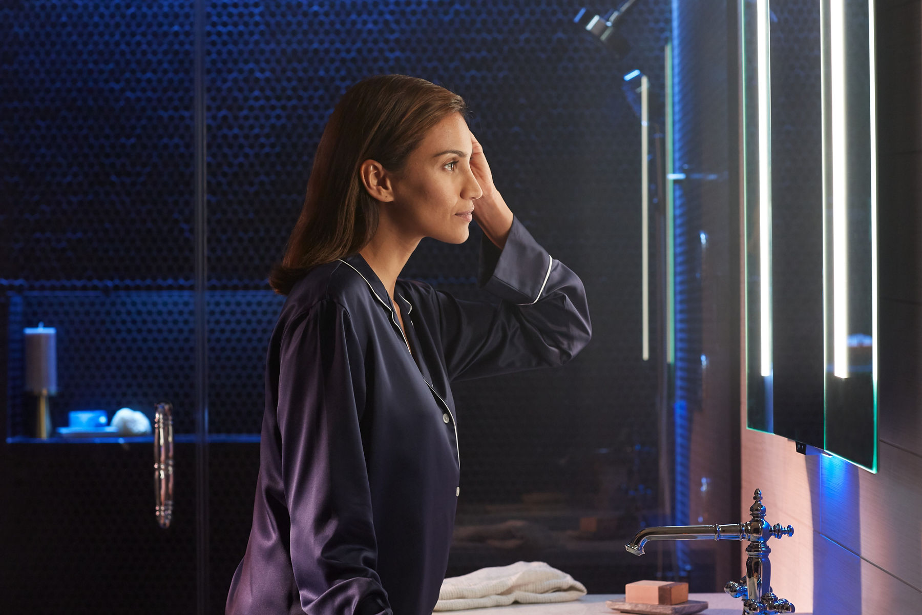 Closeup of woman, in a transitional bathroom, standing in front of an illuminated Verdera Medicine Cabinet with Amazon Alexa