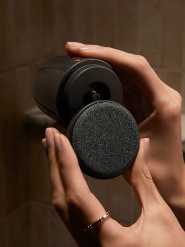 A close-up portrait product shot of a black-toned body scrubber that is opened.