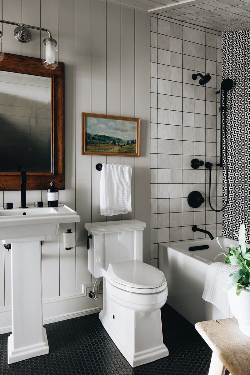 Une salle de bain avec lavabo sur colonne Tresham de KOHLER blanc, toilette Tresham blanche et baignoire-douche avec carreaux noirs et blancs contrastants.