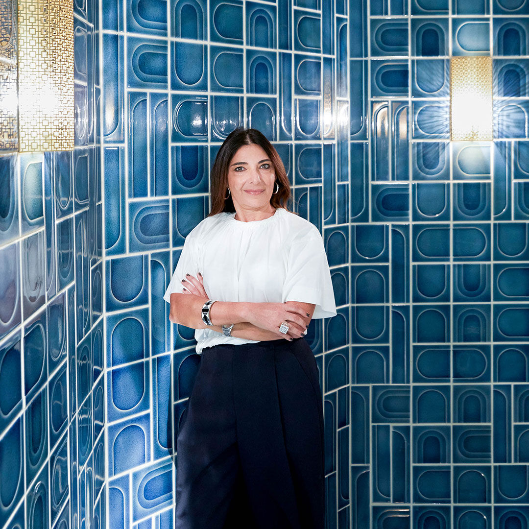 La designer Nada Debs dans l’espace qu’elle a conçu en utilisant les tuiles Waste Lab avec des arches et des nuances de bleu variées.