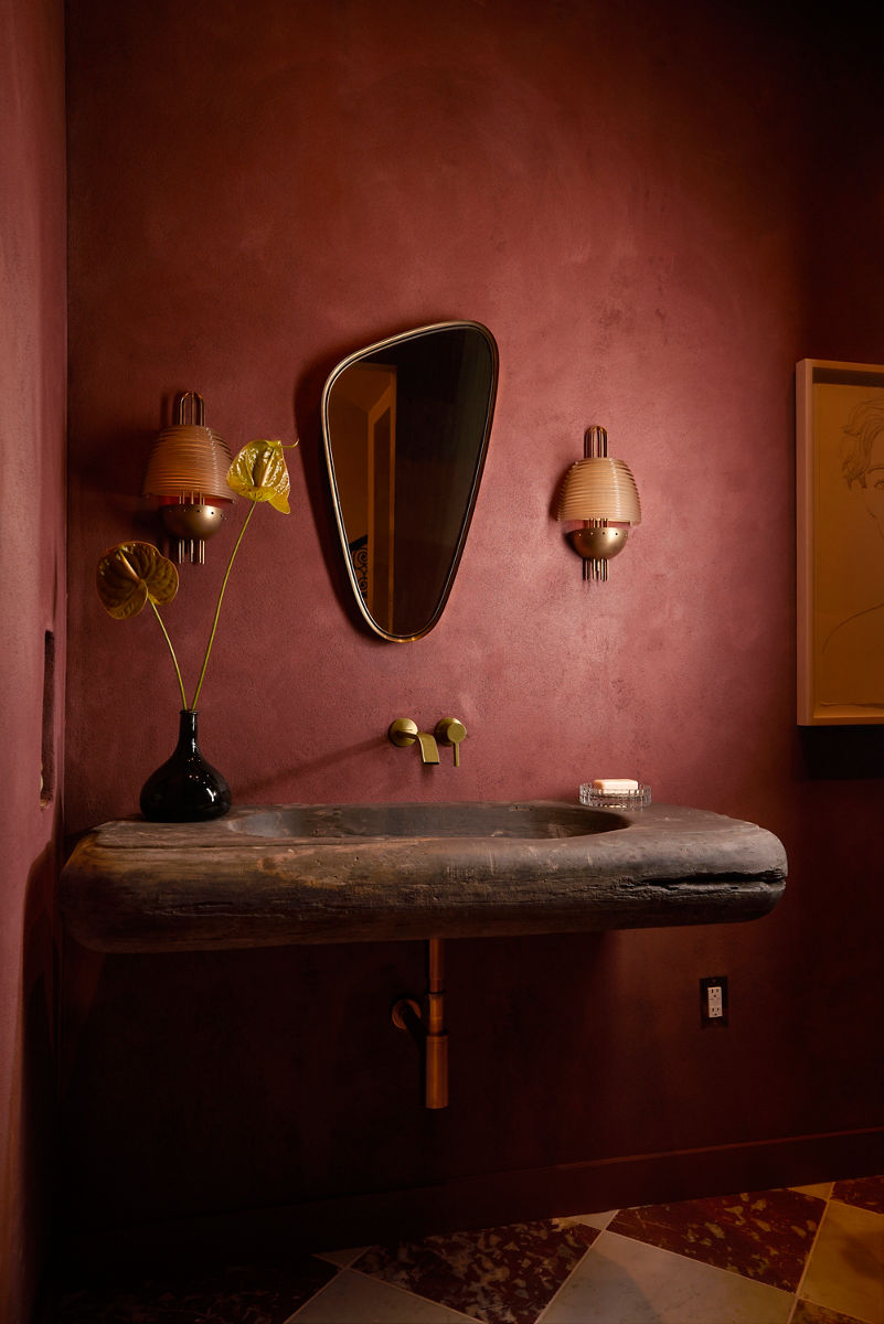 Un plan rapproché d’une salle de bain marron dotée d’un lavabo doré avec poignée fixée au mur. Le lavabo est fait de granite brun.