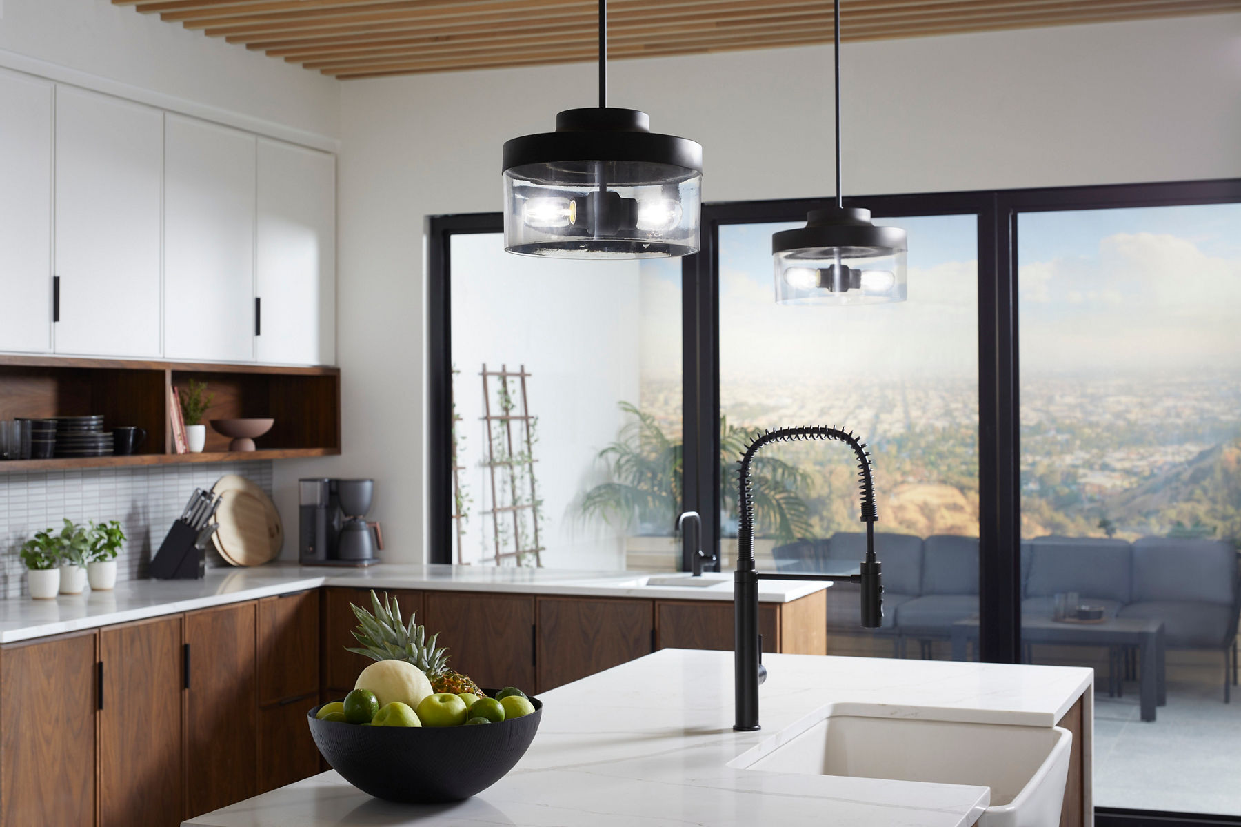 A black semi-professional kitchen faucet on an island of white stone with a apron-front white sink.
