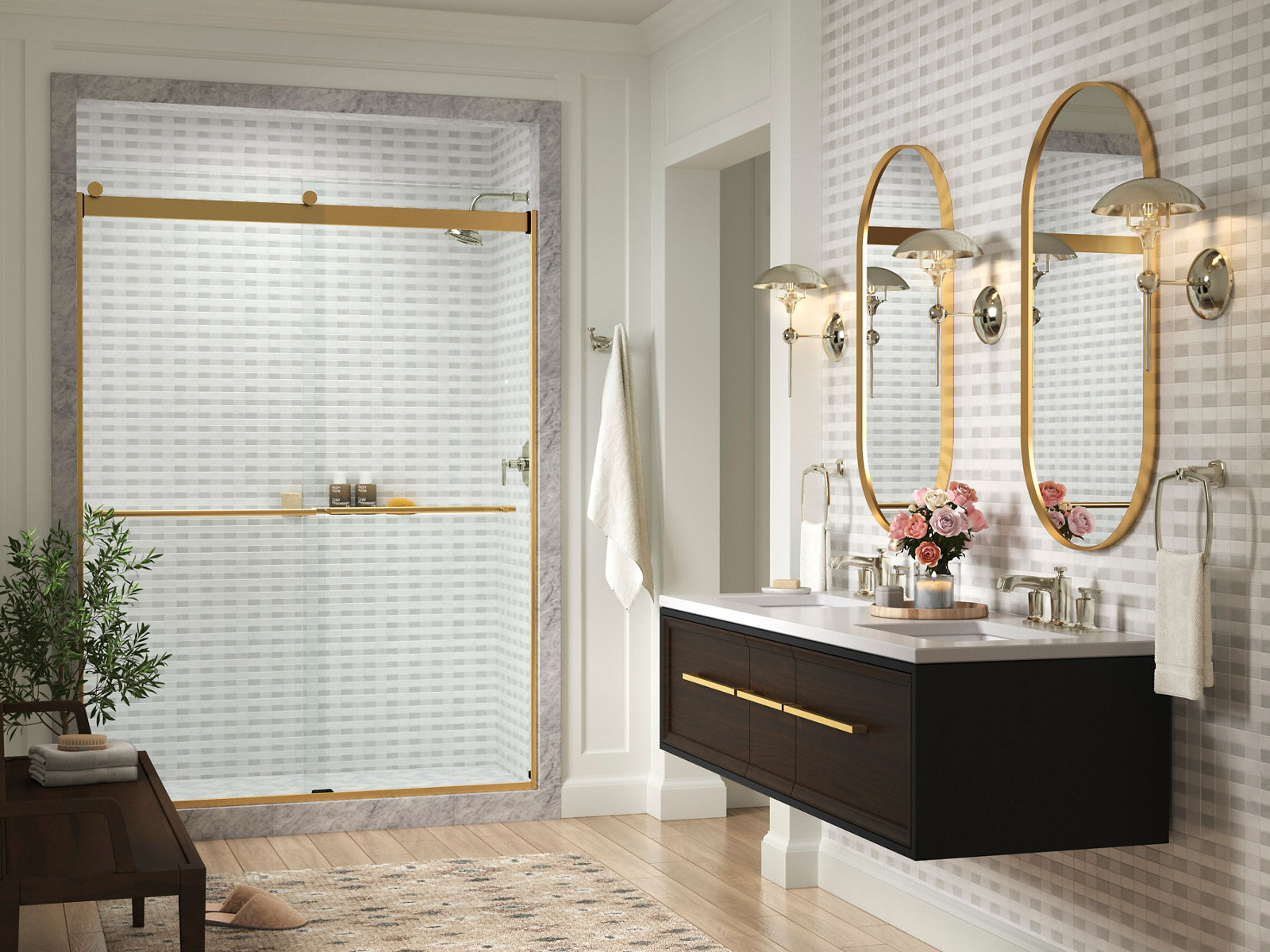 A bathroom with checkered flooring, a white freestanding bath, a wood-grain double vanity with gray counter tops, and brushed brass finishes throughout.