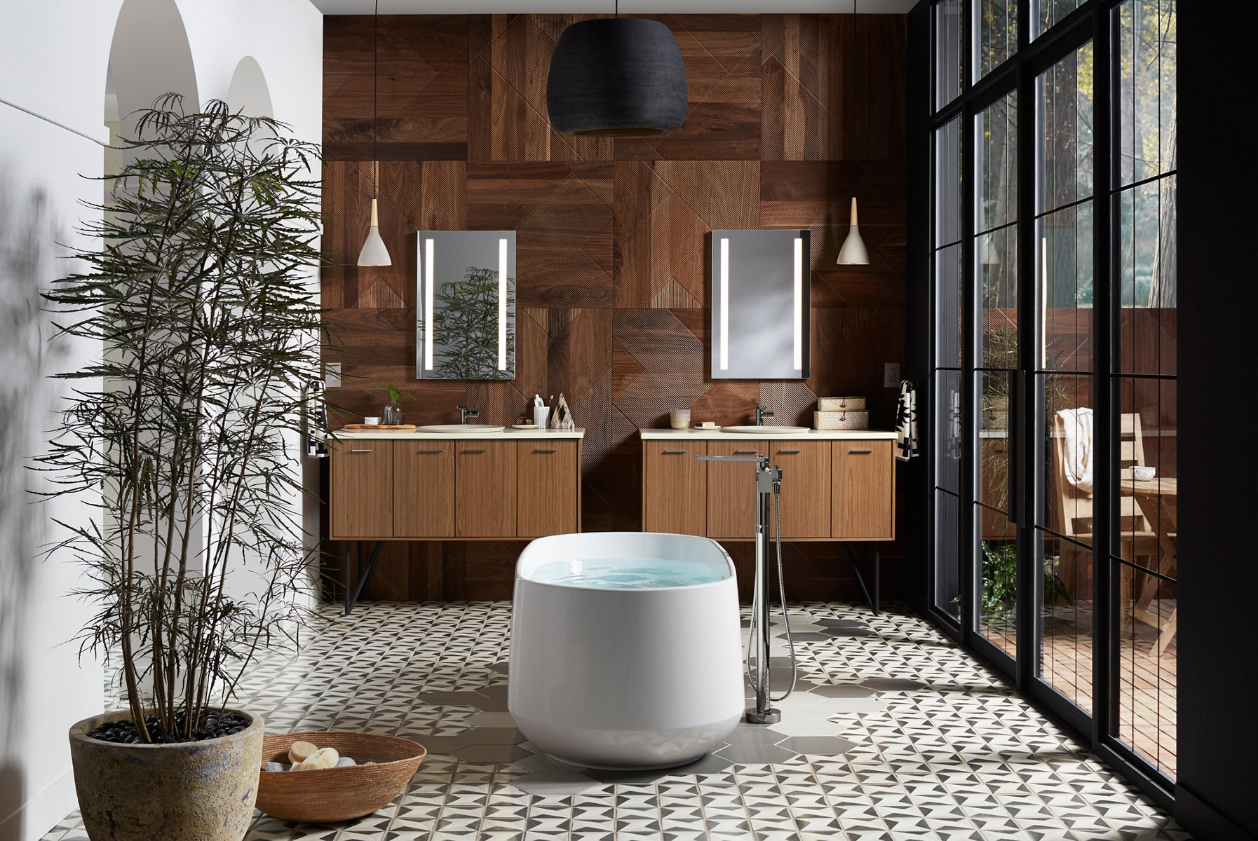 Une baignoire autoportante blanche devant deux espaces de style assortis avec des meubles-lavabos en bois et des miroirs éclairés.